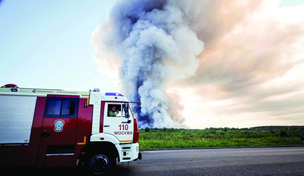 Firefighters drive past the smoke of a fire at the Russian e-commerce firm Wildberries' logistics complexes in the town of Elektrostal. — AFP