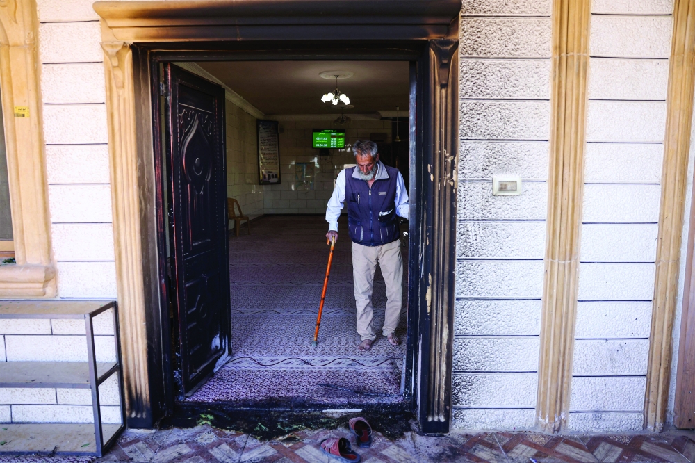 A Palestinian man checks the torched entrance at the damaged Al Taqwa Mosque. — AFP