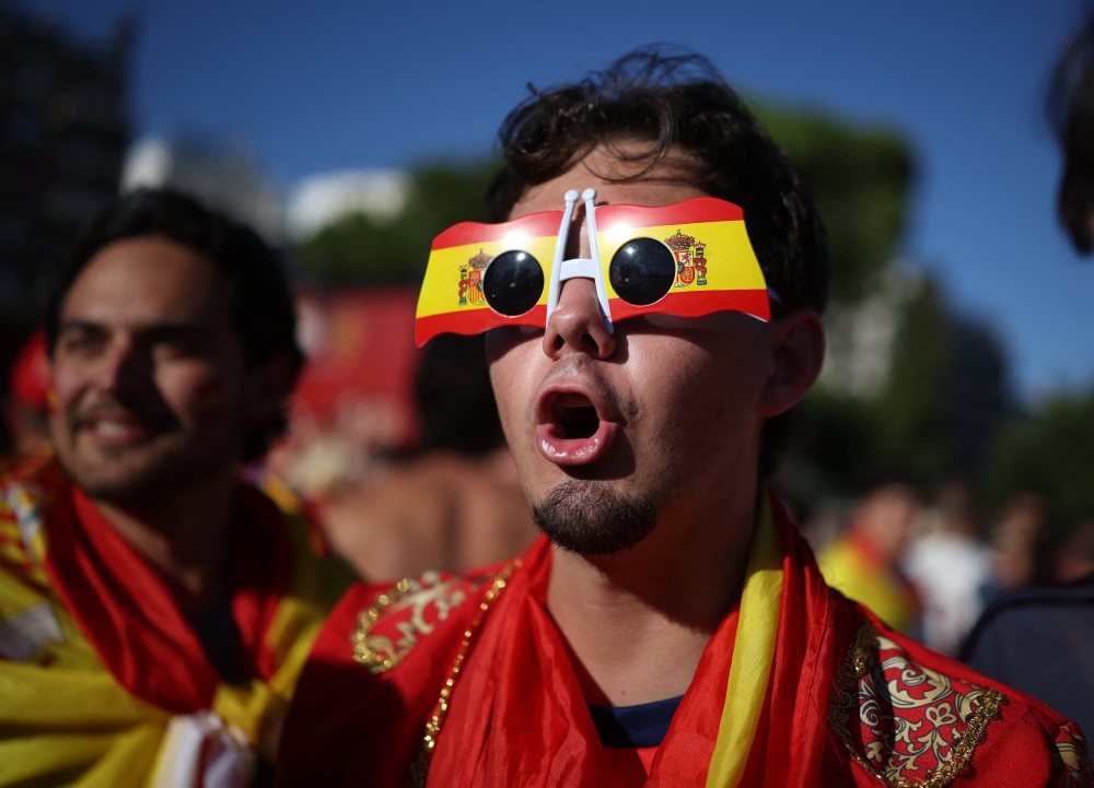 Spain fan wearing novelty glasses in the national colours gathers. — Reuters 