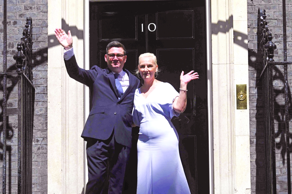 Britain's new PM Andy Burnham and his wife Marie-France van Heel pose on the steps of 10 Downing Street. — AFP
