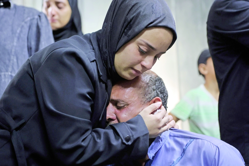 Mourners weep next to the body of one of the Palestinians in Gaza. — AFP