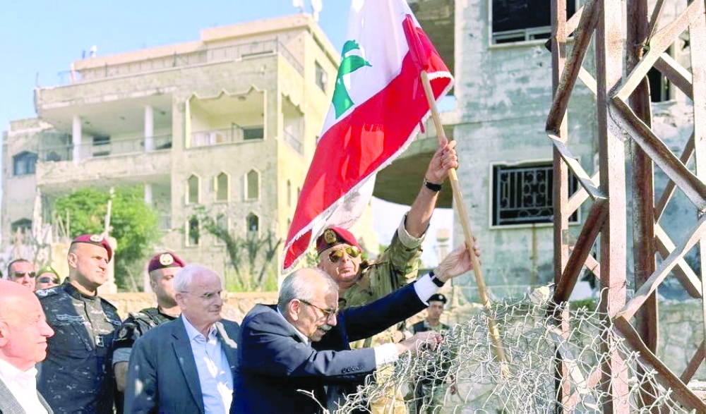 Lebanese PM Nawaf Salam plants a Lebanese flag in the ground during a visit to Zawtar Al Gharbiya. — Reuters