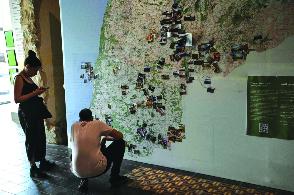 Visitors look at photographs pinned to a map of southern Lebanon as they tour "Hkeeli ya Jnoub" ("Tell me, O south")— AFP