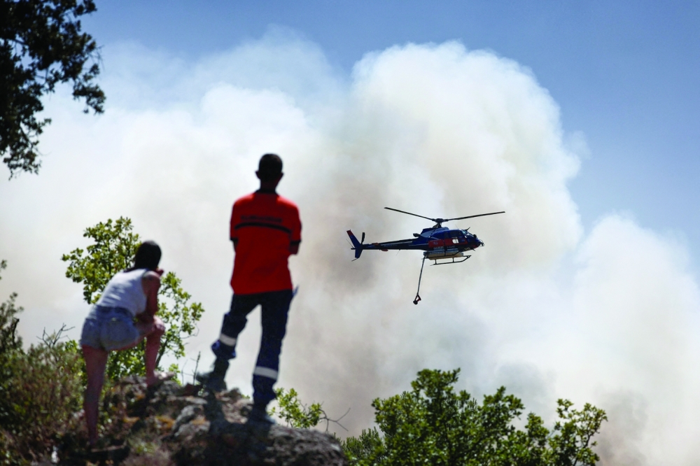 Water-bombing helicopter drops water over a burning area during a wildfire near Cotignac, southeastern France. — AFP
