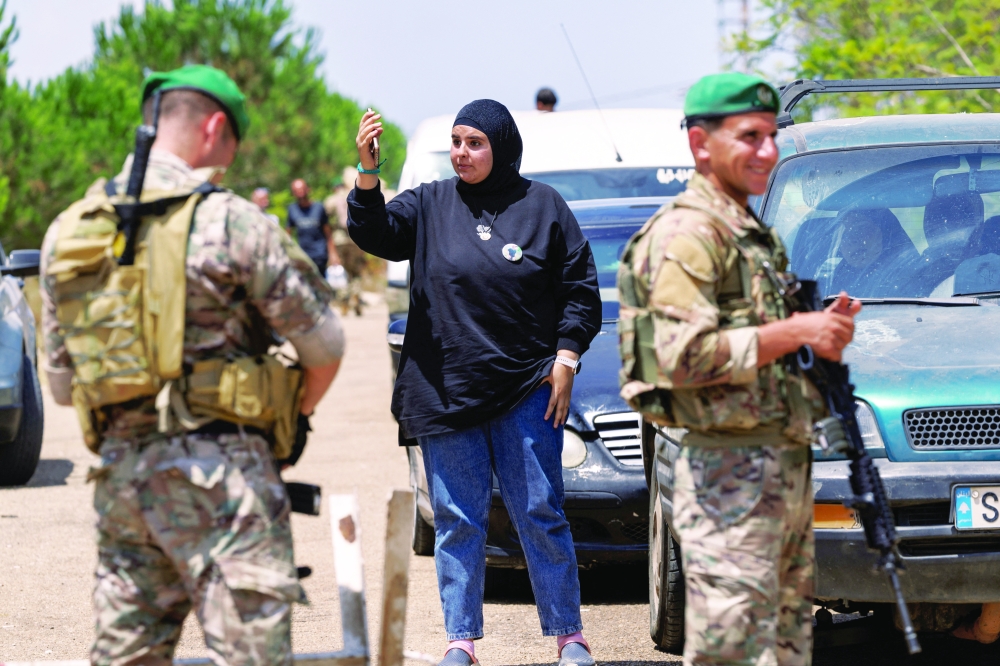 Lebanese army officers stand guard as a resident reacts while waiting to return to her home at the entrance to Zawtar al-Gharbiyeh. — Reuters