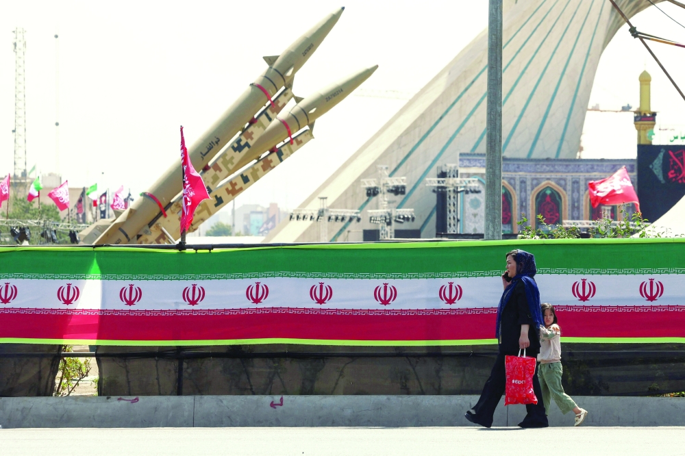 A woman and a child walk past Iranian-made Zolfaghar missiles displayed at Azadi Square in Tehran. — AFP
