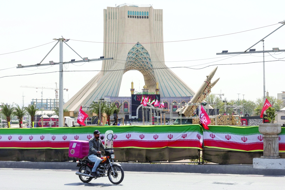 A man rides past Iranian-made Zolfaghar missiles displayed at Azadi Square in Tehran. — AFP