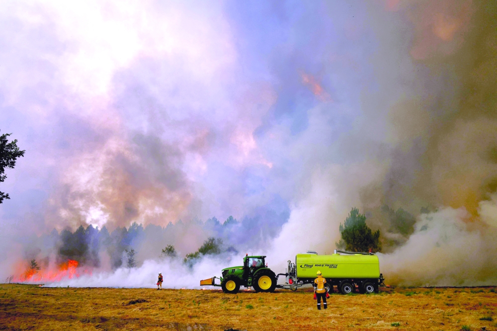 Firefighters use counterfires to remove vegetation ahead of a wildfire, creating a fuel-free buffer zone in Marcheprime, west of Bordeaux. — AFP