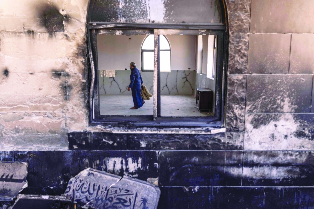 A Palestinian man prepares to pray at a mosque allegedly burned by Israeli settlers in the village of Qusra, in the West Bank. — AFP