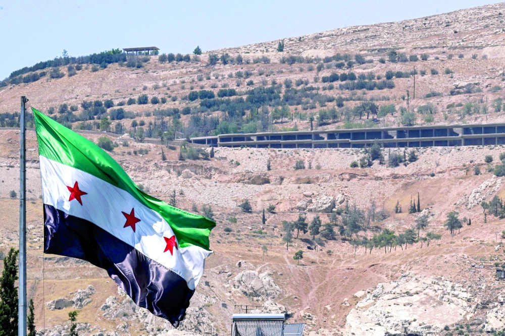 The Syrian flag flies at the Umayyad Square in Damascus on July 22, 2026, with Mount Qasioun pictured in the background. Syria’s new leaders, who inherited a dilapidated economy, are trying to attract capital without waiting for the full lifting of international sanctions. (Photo by LOUAI BESHARA / AFP)