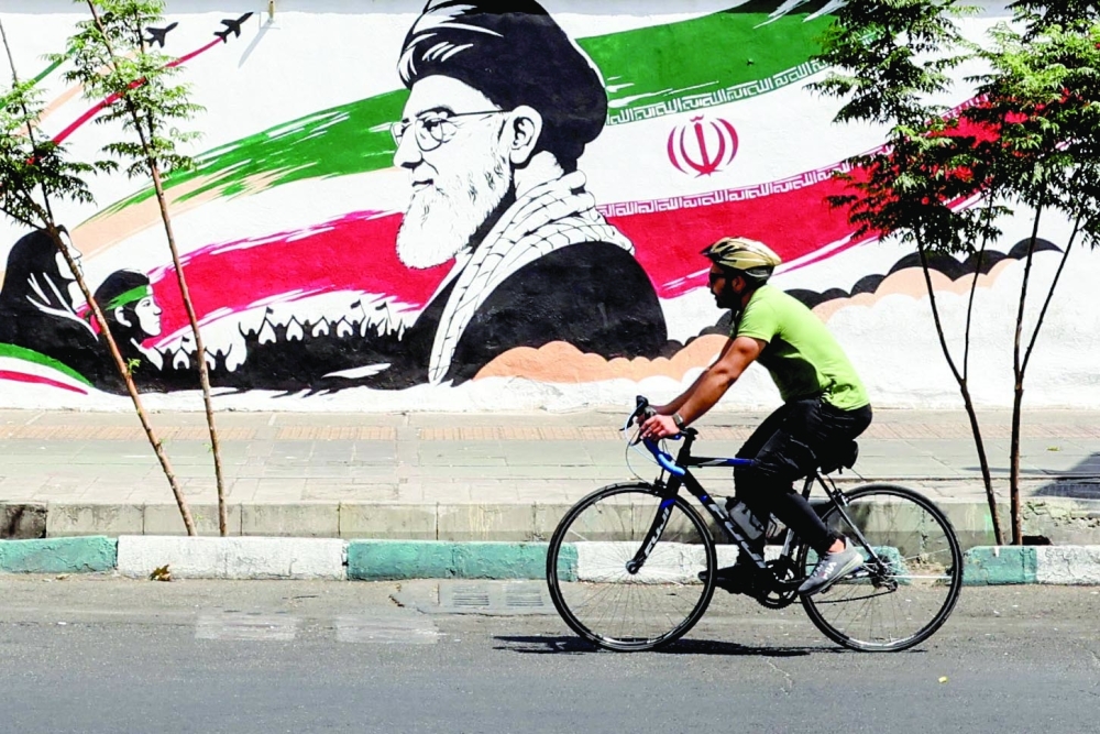 A man cycles past a mural depicting late Iranian supreme leader Ayatollah Ali Khamenei in Tehran on July 24, 2026. Iran's army said on July 24 it carried out drone strikes against several American military facilities and bases in Bahrain and Jordan in retaliation for the latest US attacks against the Islamic republic. (Photo by AFP) / NO Access Israel Media/Persian Language TV Stations Outside Iran / Strictly No Access BBC Persian / VOA Persian/Manoto TV / Iran International
/ Radio Farda --
Attention editors: AFP covers the war in the Middle East through its extensive regional network, including bureaus in Tehran, Jerusalem, and several neighboring countries. Since the start of the conflict, journalists have been working under increasingly restrictive conditions. Authorities in several countries have limited reporters' movements, photo and live video coverage from sensitive locations. Some governments and armed groups have banned images of missile or drone strikes and other security-related sites.