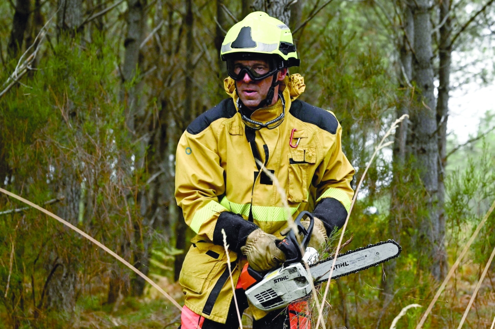 A firefighter clears brush  in Saint-Jean-d'Illac, west of Bordeaux, on Monday in the Gironde region, southwestern France. — AFP