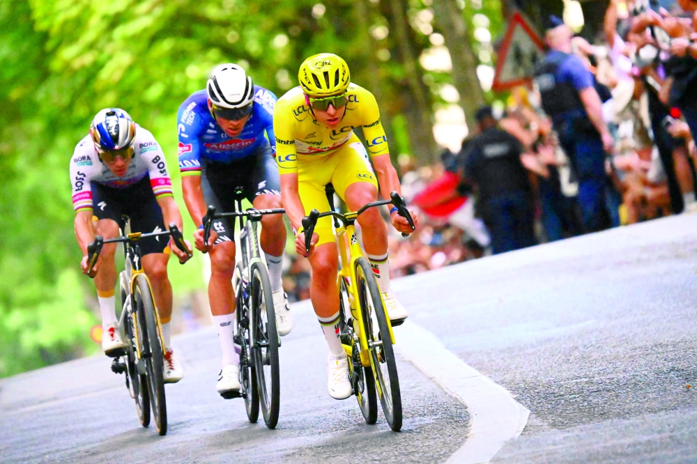 UAE Team Emirates - XRG's Slovenian rider Tadej Pogacar wearing the overall leader's yellow jersey, Alpecin - Premier Tech team's Dutch rider Mathieu van der Poel and Red Bull - BORA - hansgrohe team's Belgian rider Remco Evenepoel cycle on the Butte de Montmartre during the 21st stage of the 113th edition of the Tour de France cycling race. — AFP