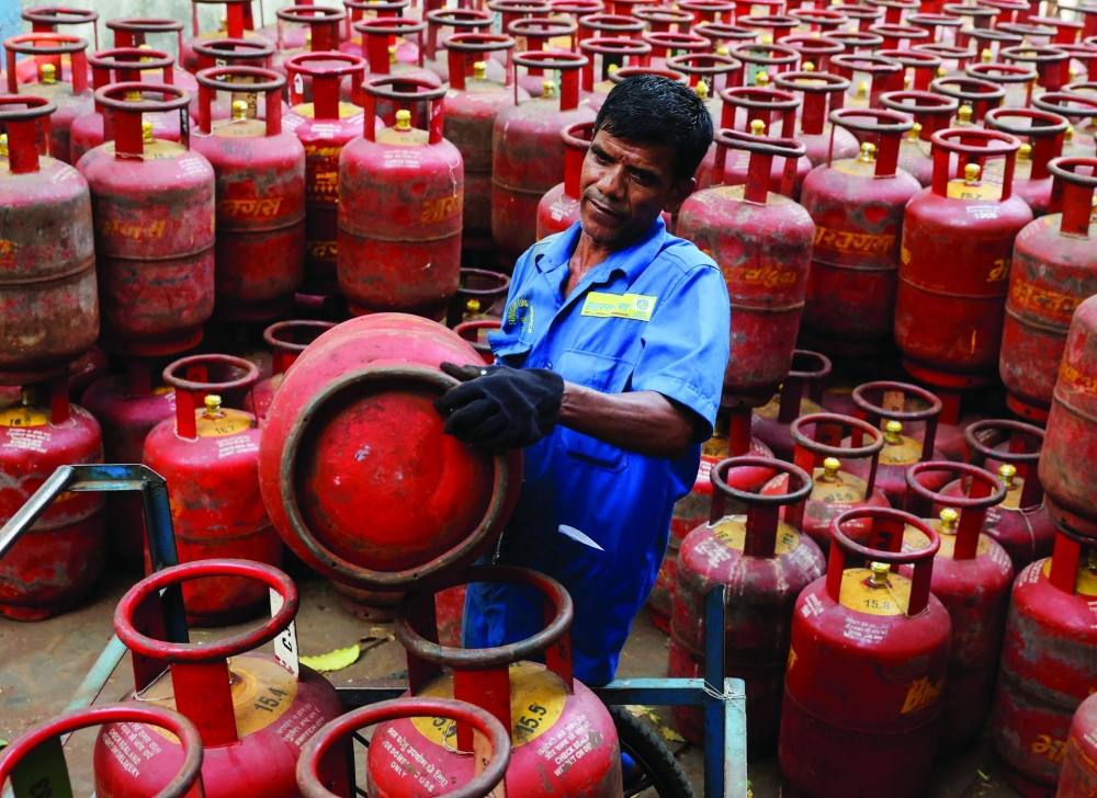 A man loads LPG cylinders onto a cart at a warehouse in Mumbai