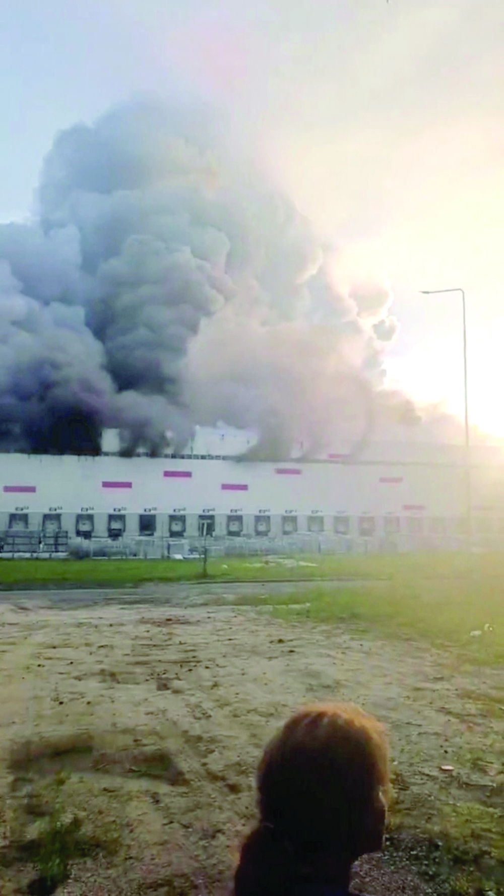 A woman looks on as smoke billows from a Wildberries warehouse after a fire broke out at the facility, in Ryazan region, Russia. — Reuters