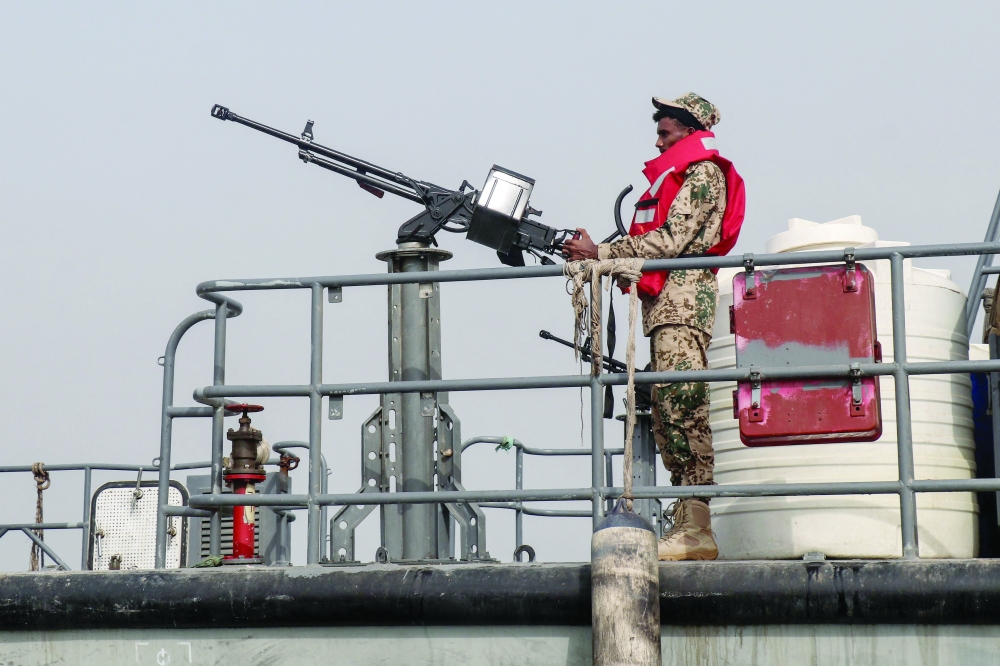 A sailor from Yemen's government navy stands at a machine-gun position aboard a vessel patrolling a shipping lane off Hanish Island in the Red Sea