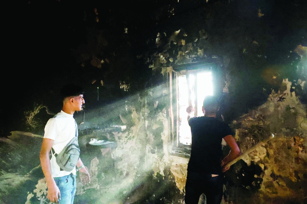 Palestinian men inspect a burnt-out room following an attack by Israeli settlers in Sarra near Nablus 