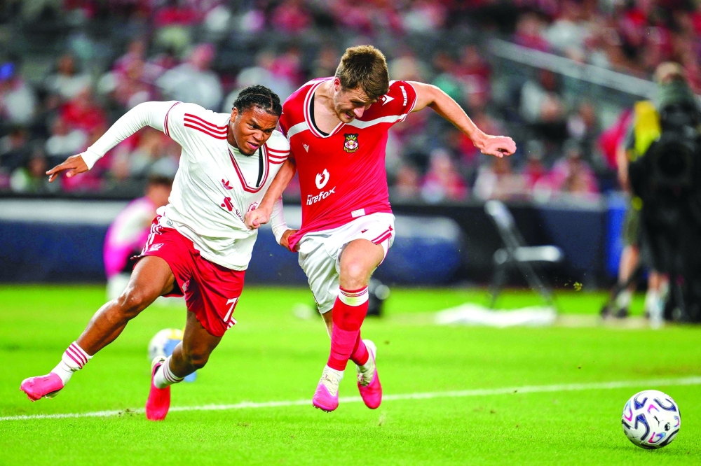 Liverpool's English striker Rio Ngumoha and Wrexham's English midfielder George Thomason fight for the ball. — AFP