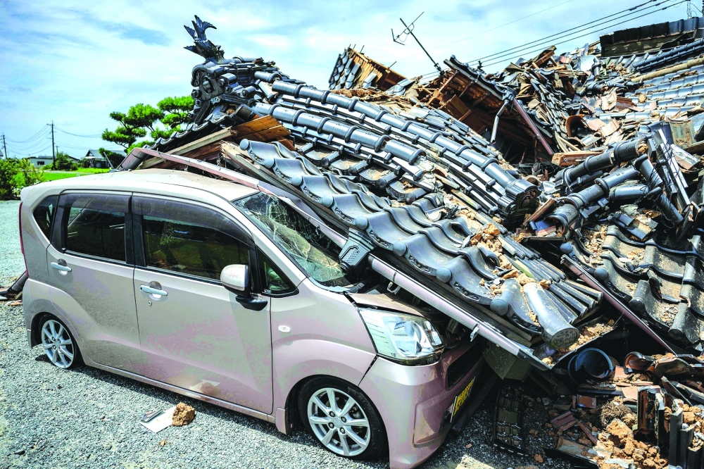 A house is seen collapsed onto a car in Hikawa, Kumamoto Prefecture after an earthquake struck the area. — AFP