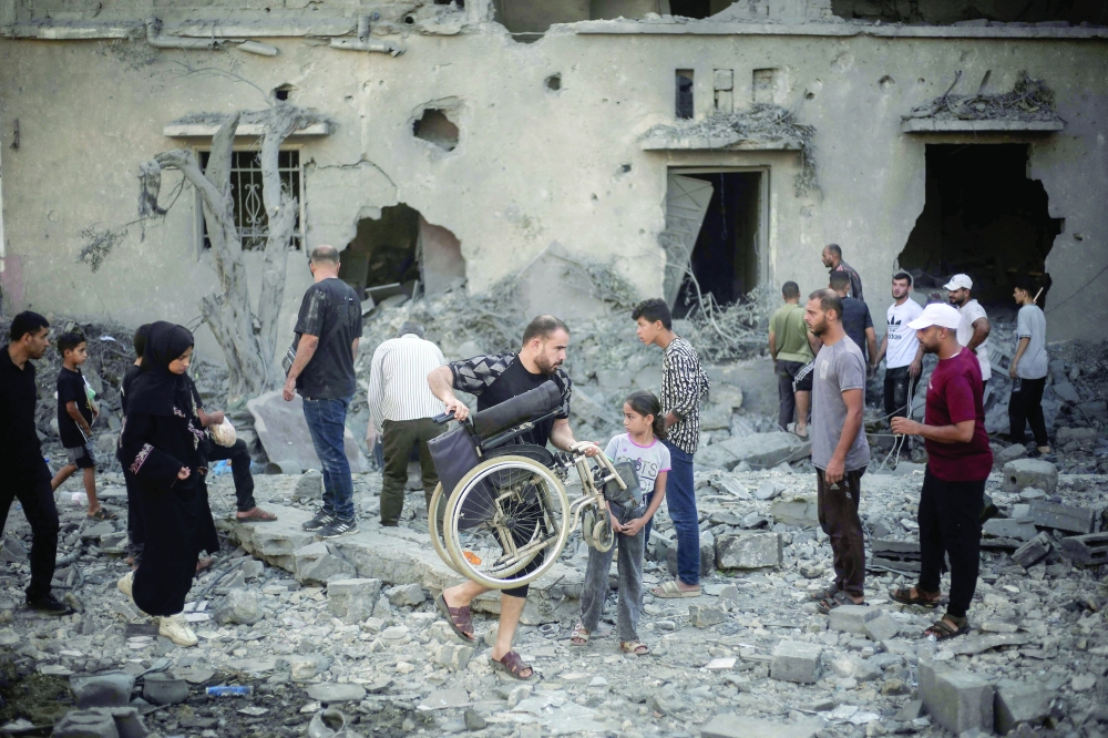 Palestinians inspect damaged buildings after they were targeted by Israeli strikes in Deir al Balah, central Gaza Strip on Wednesday. — AFP