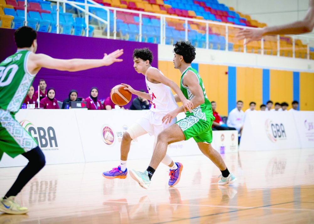 An Oman player drives towards the basket under pressure from the Saudi defence.
