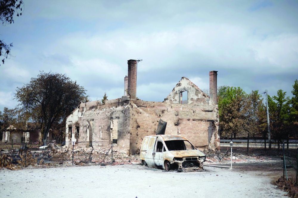 A house and a car burnt following a wildfire in Lanton, southwestern France. - AFP