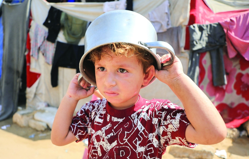 A child wears a pot on his head as displaced Palestinians shelter at a tent camp, in Gaza City, on Friday. — Reuters