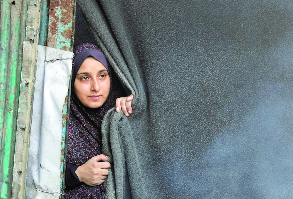 A woman looks out from a tent as displaced Palestinians shelter at a tent camp, in Gaza City, on Friday. — Reuters