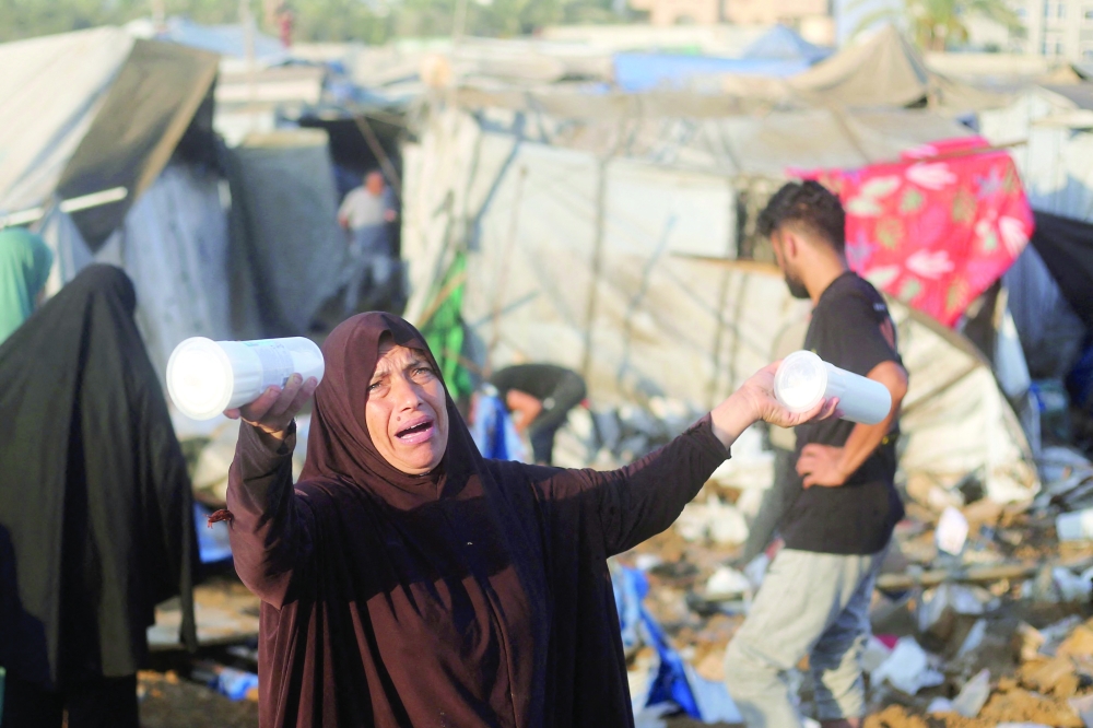 A displaced Palestinians woman reacts holding up containers following an Israeli airstrike that targeted the medical supplies and pharmaceuticals warehouse of Al-Aqsa Martyrs Hospital, in Deir al-Balah, on Saturday. — AFP