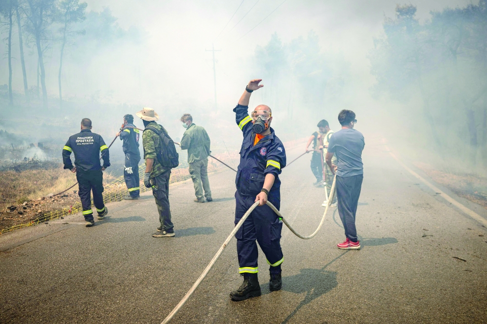 Volunteers and Greek firefighters work to extinguish a wildfire near Porto Germeno, northwest of Athens. — AFP