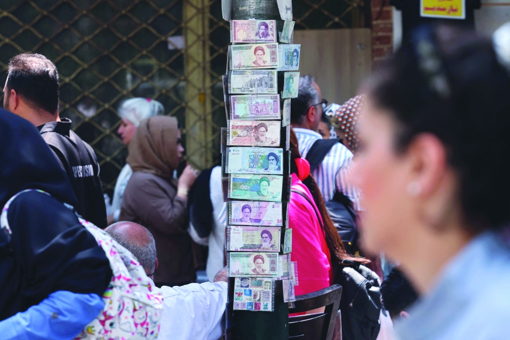 People walk past shops and stalls as they visit the Grand Bazaar in Tehran on Sunday. — AFP