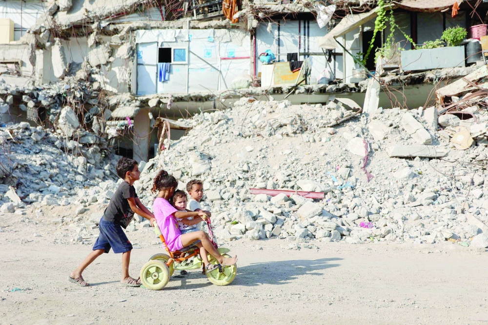 Palestinian children play near the rubble of destroyed buildings in Gaza City. — AFP
