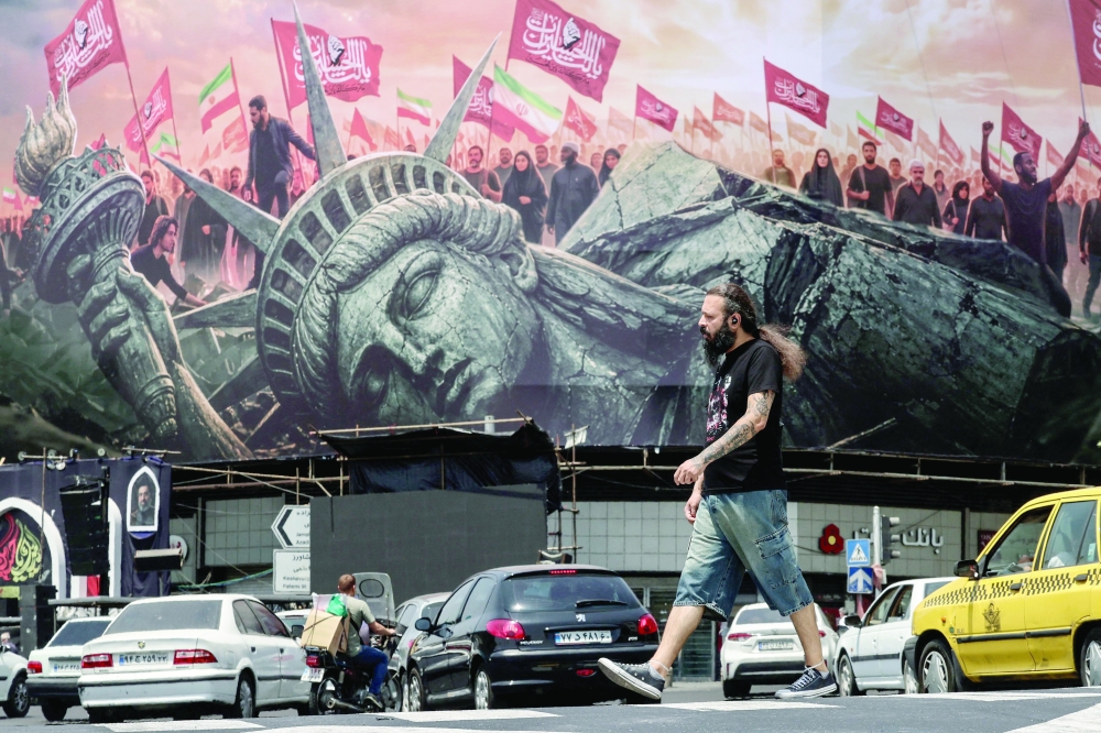 An Iranian man walks past an anti-US billboard at Enghelab Square in central Tehran. — AFP