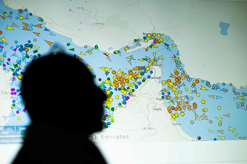 A photo illustration taken in Nicosia on May 4, 2026, shows a person in front of a large screen displaying vessel movements in the Strait of Hormuz on a ship-tracking website. 
