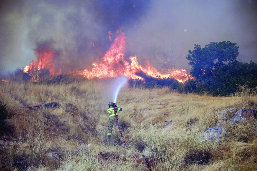 A firefighter works to extinguish a wildfire raging since four days in the Megara Region, west of Athens on Tuesday. — AFP