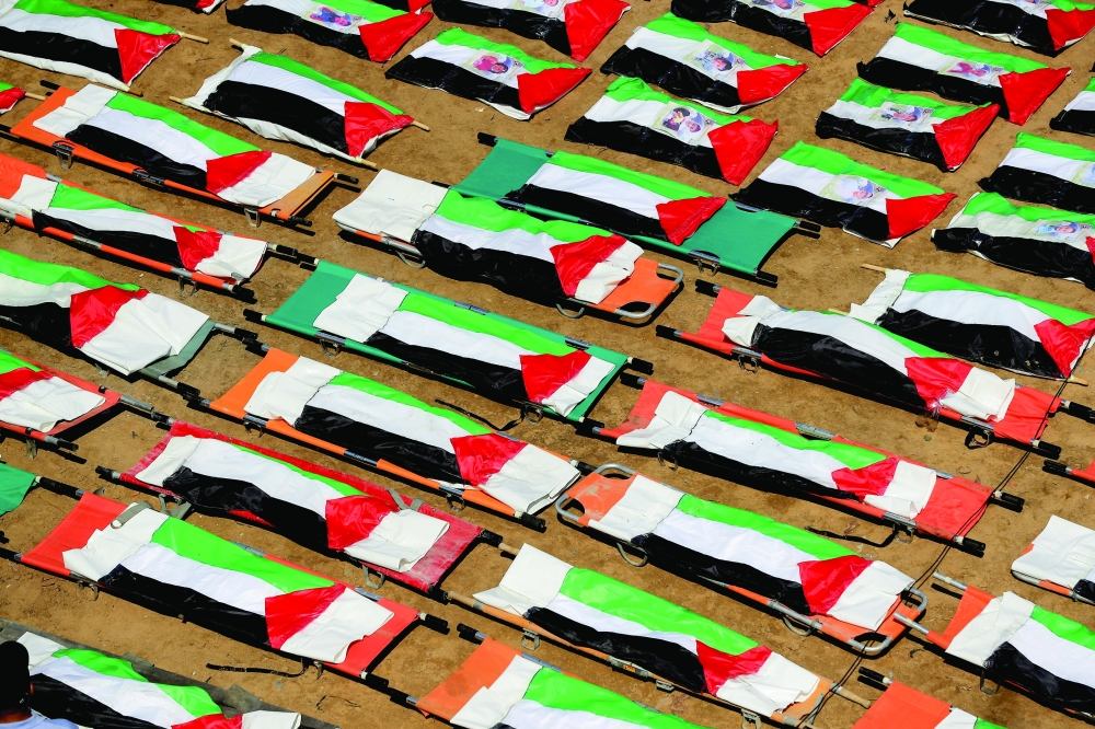 Bags containing the remains of Palestinians, draped in Palestinian flags, are lined up during the funeral of 112 members of the Hassayna and Abu Sharia clan, who were killed in an Israeli strike in 2023 and whose remains were recovered from beneath the rubble, according to Gaza's Civil Defense, in Gaza City, on Tuesday. — Reuters
