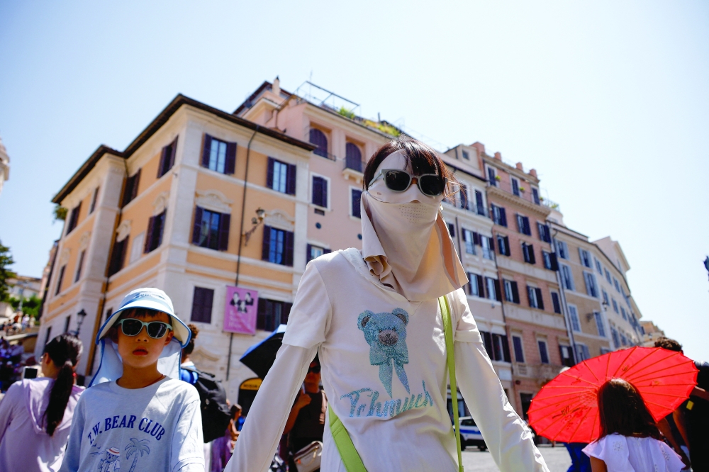 A woman wearing a face cover walks with a child near the Spanish Steps during a heatwave in Rome, Italy. — Reuters