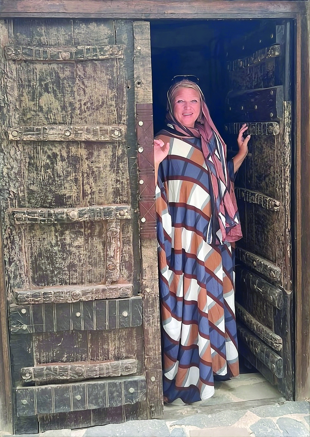 Carmen Storck stands in the ornate wooden doorway of a traditional house in Salalah
