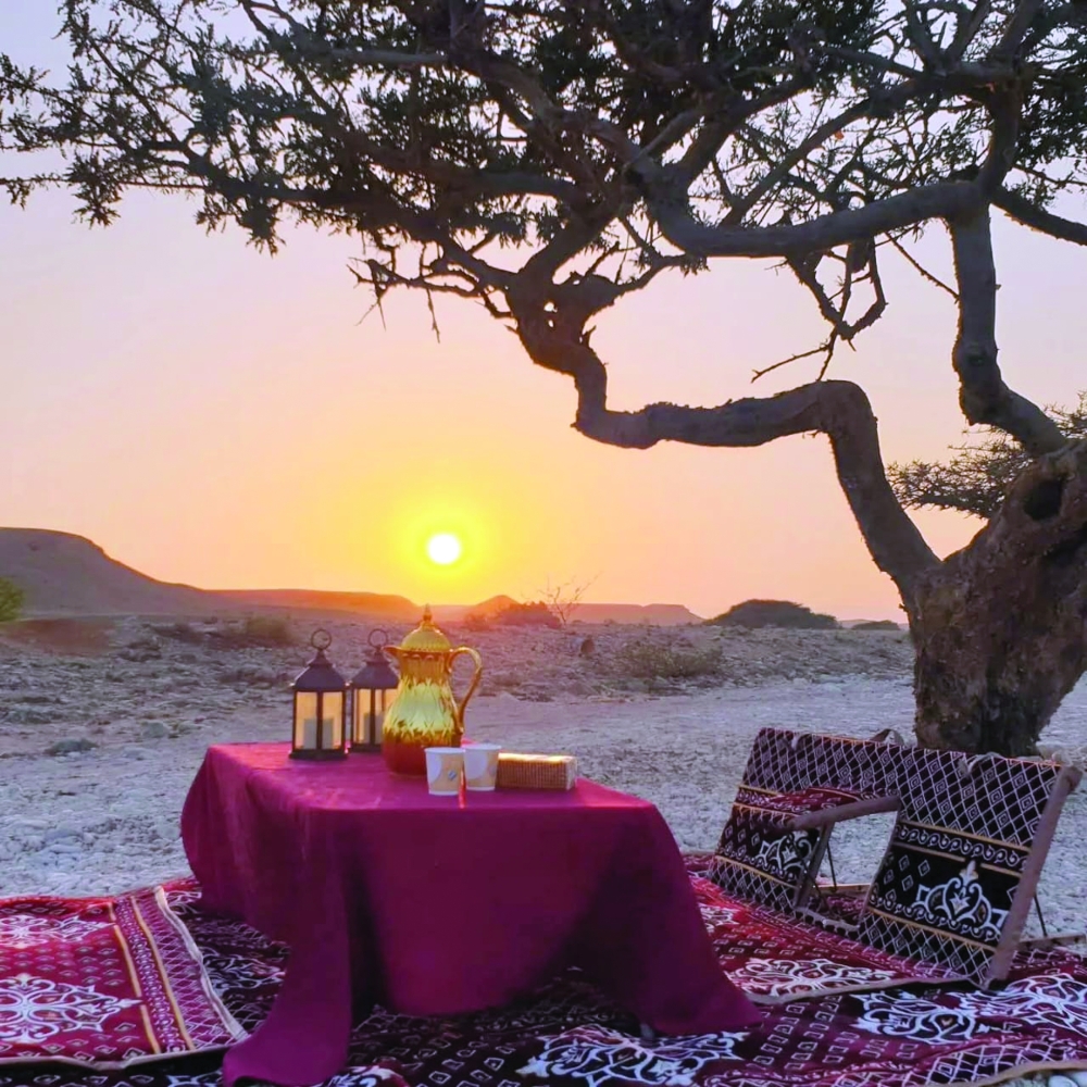 Traditional coffee setup under a frankincense tree at golden hour in the desert near Salalah