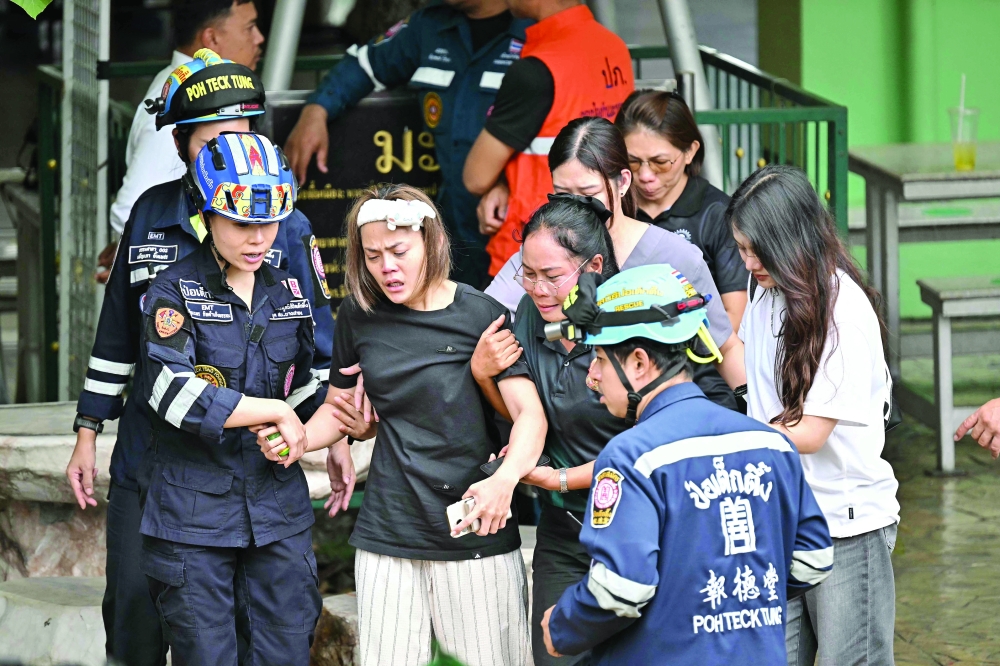 The wife of a teacher who was killed in a school shooting is led to an ambulance in Bang Kruai district, Nonthaburi province, north of Thailand's capital Bangkok. — AFP