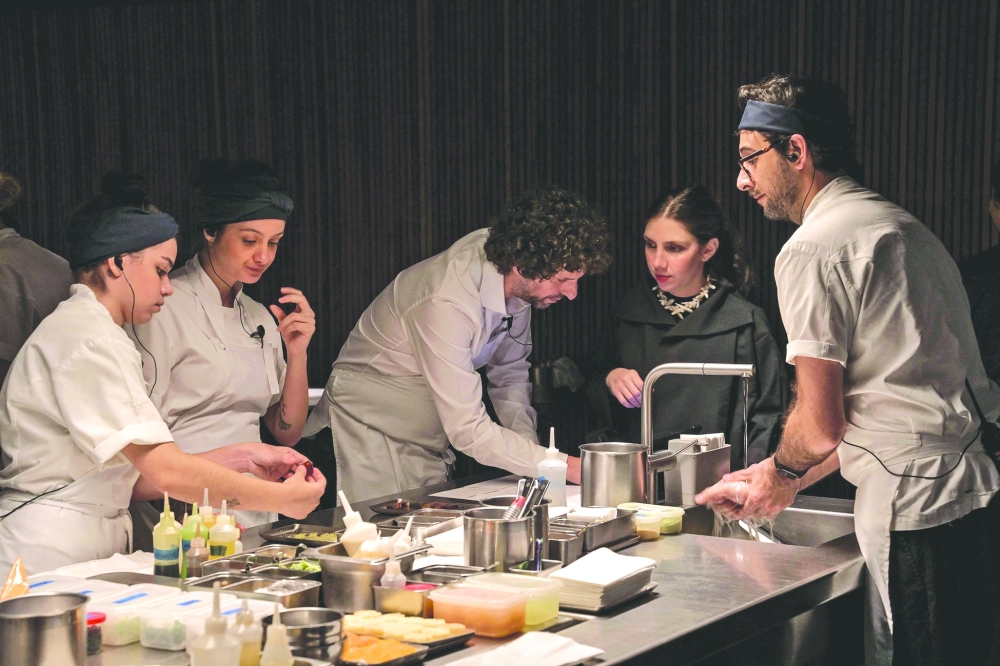 Ivan Ralston (C) and Katherina Cordas (2-R), owners of the TUJU restaurant, work with the cooks in the kitchen, in Sao Paulo, Brazil the first restaurant in Latin America to receive three Michelin stars. — AFP