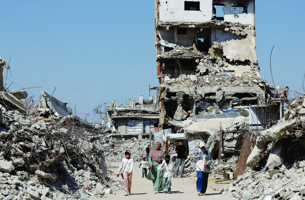Palestinians walk past the rubble of residential buildings destroyed during the war, at Jabalia refugee camp in the northern Gaza Strip, August 5, 2026. REUTERS/Mahmoud Issa
