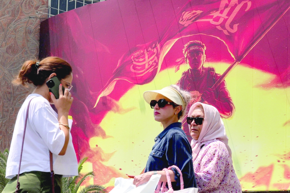 Women walk past a billboard at Valiasr Square in central Tehran on Saturday. — AFP