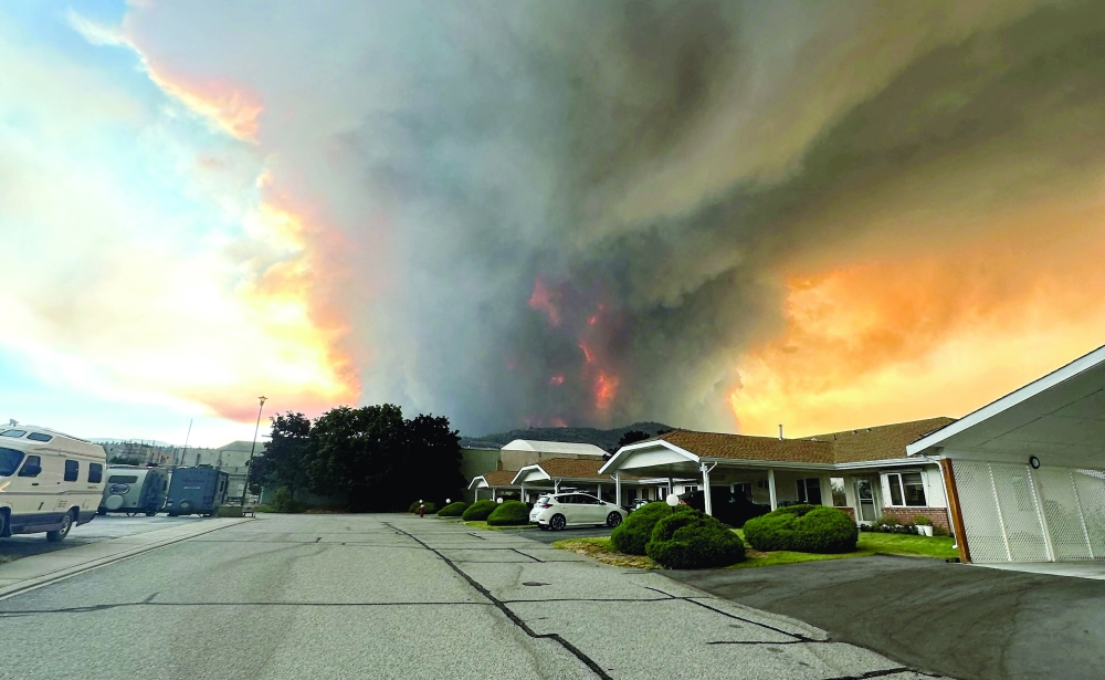 Smoke rises from the Bald Range wildfire over a residential street in Summerland, Canada. — Reuters