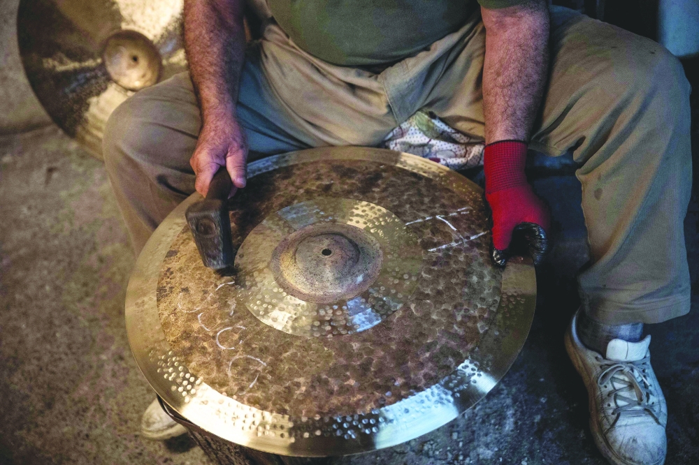 A worker hammers a cymbal at a workshop in Istanbul — AFP