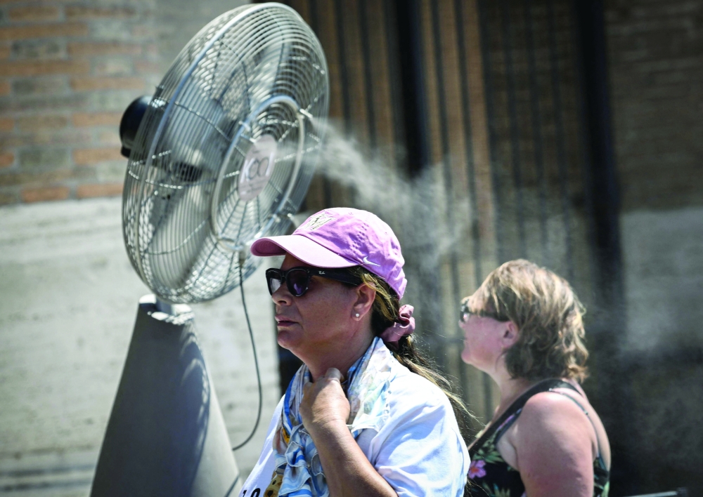 People walk past a misting fan during a heatwave in Rome at the Colosseum. — AFP