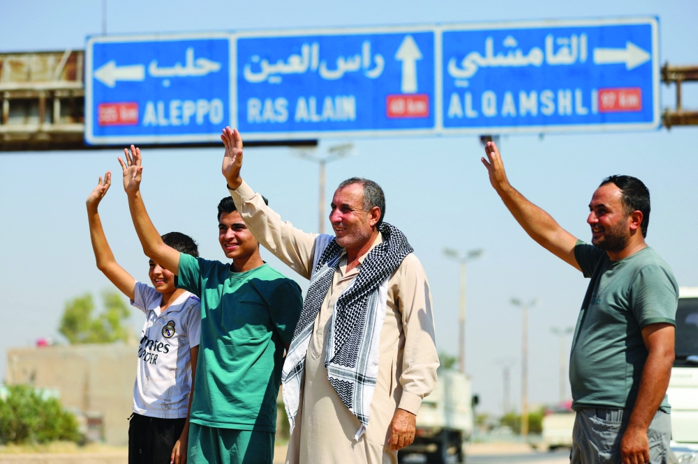 People wave to Kurds who make their way to their hometown of Ras al Ain in Hasakah, Syria. — Reuters