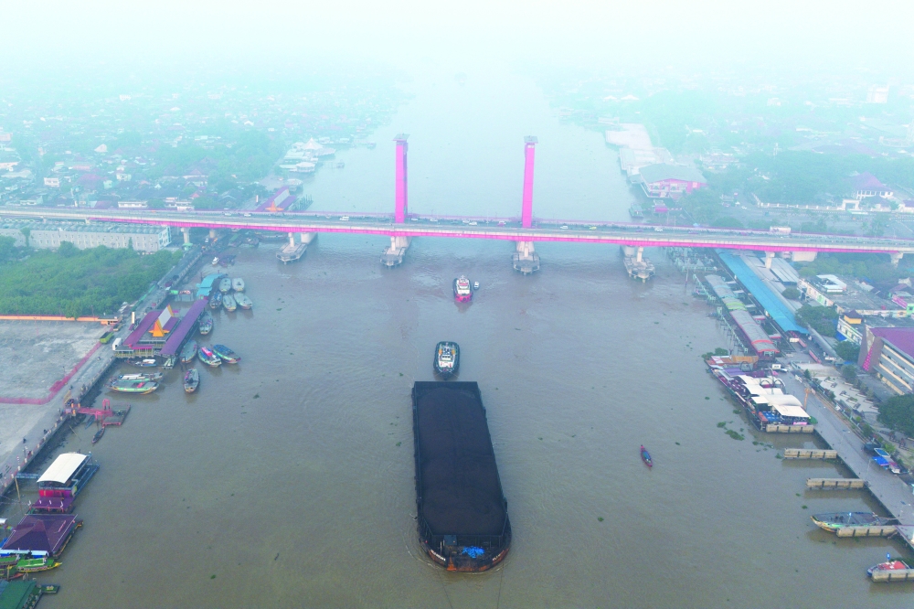 A drone view shows a tug boat pulling a coal barge along the Musi river, passing Ampera Bridge, as smog covers it due to recent wildfires in Palembang, South Sumatra province, Indonesia. — Reuters 