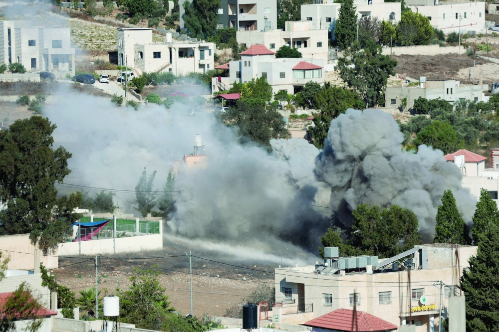Smoke rises as Israeli forces blow up the house of Palestinian Farouk Ramadan, near Nablus in the West Bank. — Reuters 