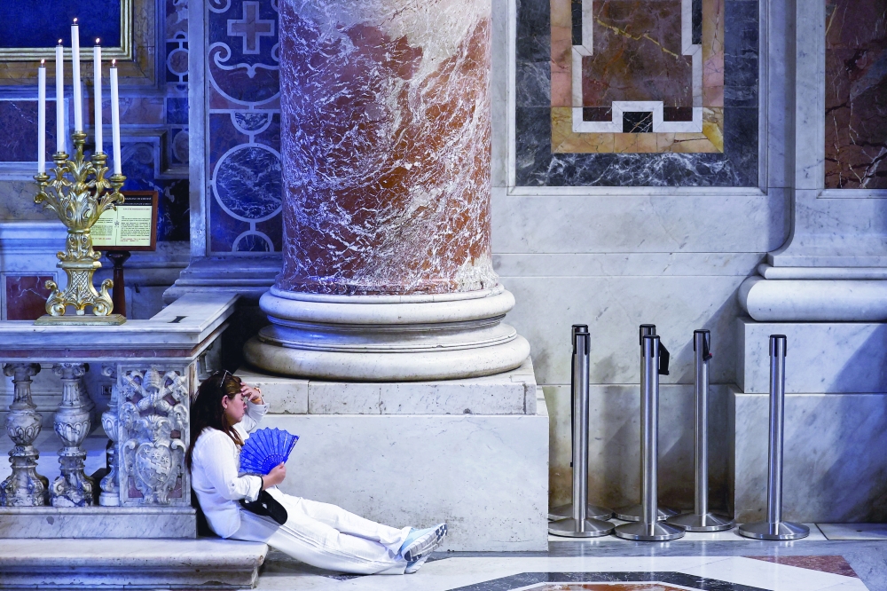 A woman uses a hand fan to cool off amid a heatwave, in St Peter's Basilica at the Vatican. — Reuters 